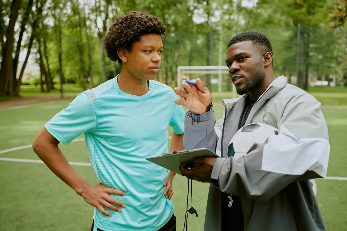 Young KC coach mentoring a young person on a Kansas City sports field